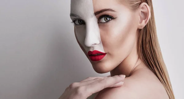 Viviendo en un mundo de rojo y blanco. Foto de una hermosa mujer con pintura facial y lápiz labial rojo sobre un fondo liso. —  Fotos de Stock