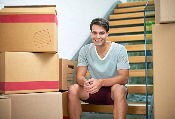 Yeni bir bölümün başlangıcı. Karton kutularla çevrili yeni evinde oturan genç bir adamın portresi.. — Stok fotoğraf