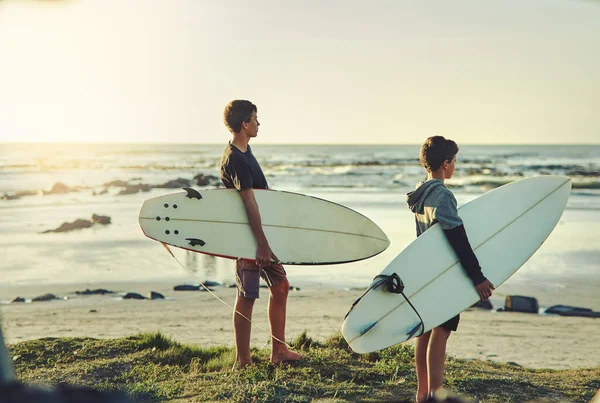 Eles têm um caso de febre surfista. Tiro de dois jovens irmãos segurando suas pranchas de surf enquanto olham para o oceano. — Fotografia de Stock