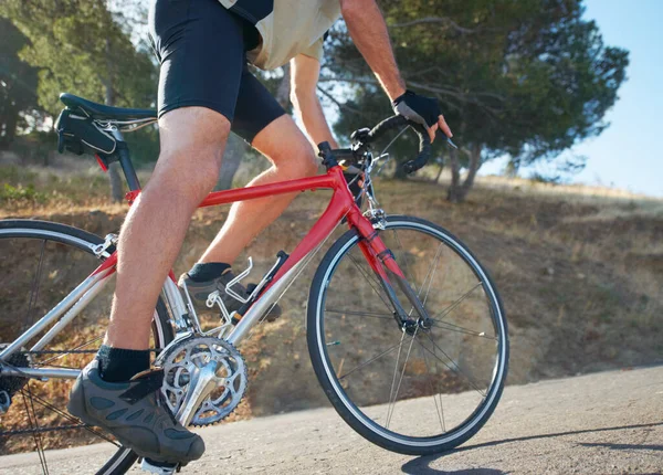 Het is lang bergop geweest. Gekropte foto van een fietser die bergop rijdt op een landelijke weg. — Stockfoto