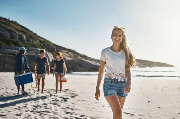 Jeg er bare glad for å være med vennene mine. Portrett av en lykkelig ung kvinne som går på stranda med vennene sine på en solrik dag. – stockfoto