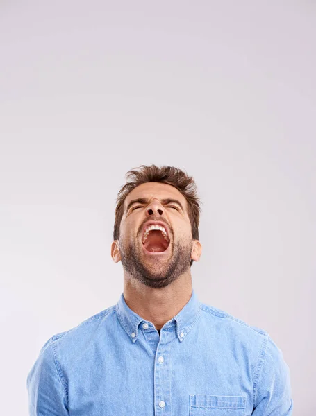 Je kunt zijn gevoelens niet verbergen. Studio shot van een knappe jonge man schreeuwen in woede tegen een grijze achtergrond. — Stockfoto