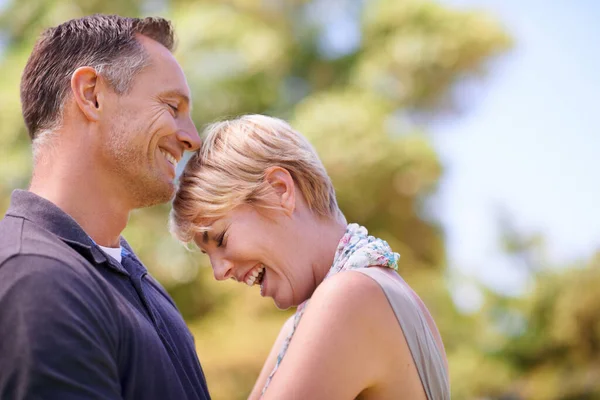 De perfecte combinatie van liefde en lachen. Shot van een volwassen paar delen van een teder moment buiten. — Stockfoto