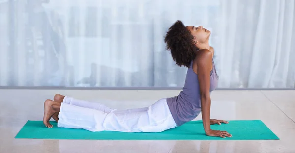 Розтягнути її спину. Знімок привабливої молодої жінки, що робить йогу на тренувальному килимку . — стокове фото