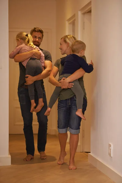 Hora de acostar a estos dos. Un disparo de padres jóvenes llevando a sus hijos somnolientos a la cama. — Foto de Stock