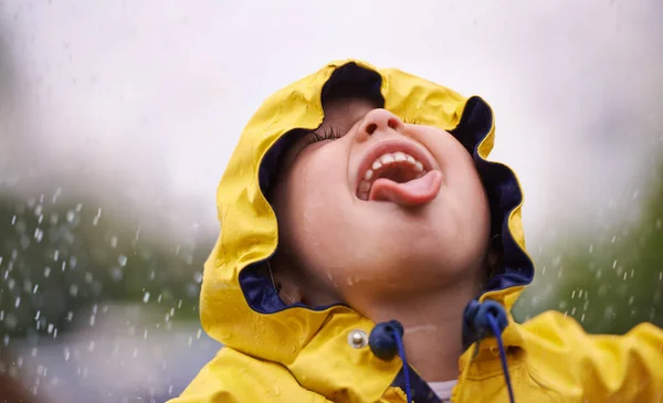 Чтобы насладиться радугой, сначала насладитесь дождём. Маленькая девочка веселится под дождем. — стоковое фото