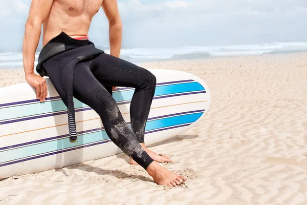 A szörfözés egy életforma. Egy fiatal férfi szörfös készül szörfözni egy forró nyári napon.. — Stock Fotó