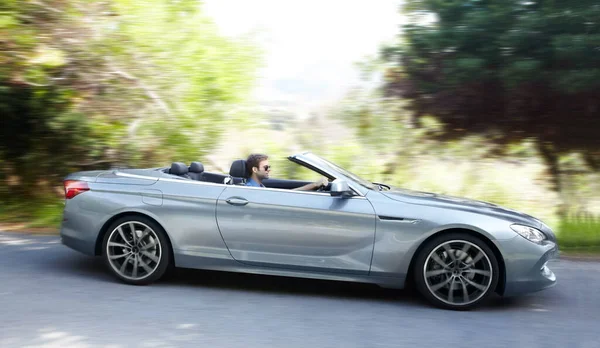 Feeling the wind in his hair. A young man driving a silver sportscar. — Stock Photo, Image