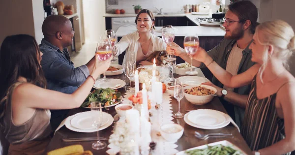 Reúne a tus amigos y deja que los buenos tiempos fluyan. Foto de un grupo de jóvenes amigos brindando con vino en una cena de Navidad. — Foto de Stock