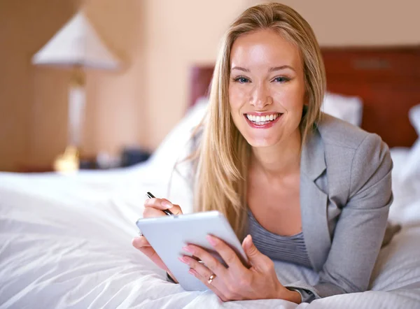 Me encantan los hoteles wifi. Una joven empresaria usando una tableta digital en un dormitorio. —  Fotos de Stock
