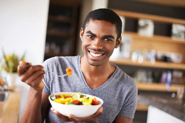 Dá uma dentada na saúde. Indoor tiro de um jovem homem negro lindo mostrando sua salada de frutas. — Fotografia de Stock