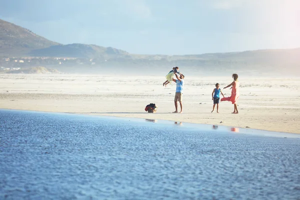 子供たちとの私たちの時間はリラックスしてやりがいがあります。ビーチで一日を楽しむ4人の家族のショット. — ストック写真