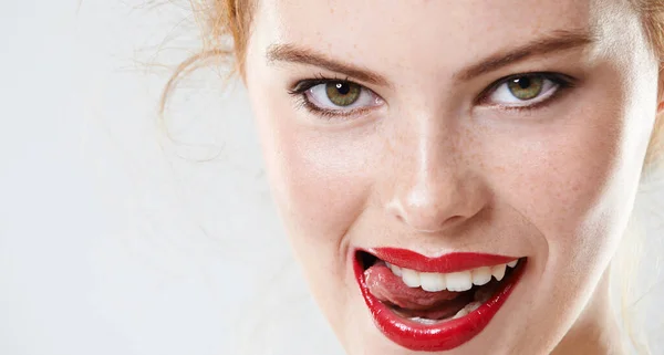 Elle est brûlante. Gros plan portrait studio d'une belle jeune femme portant rouge à lèvres mordant sa langue. — Photo