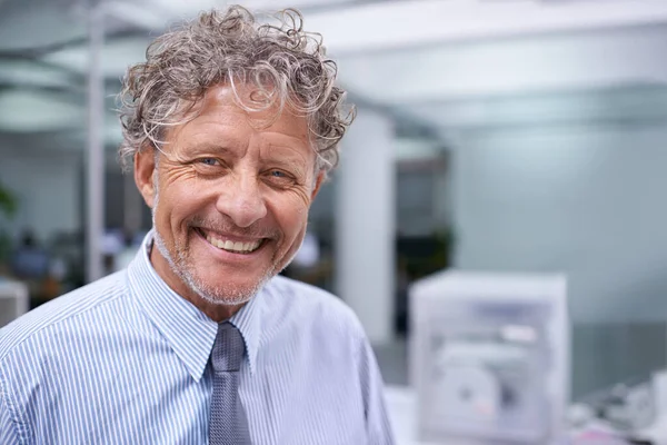 Toujours face à chaque jour de travail avec un sourire. Portrait tête et épaules d'un homme d'affaires mature dans un bureau. — Photo