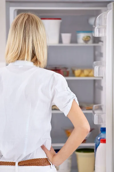 What to eat. Rearview of a young woman looking in her fridge. — Stock Photo, Image