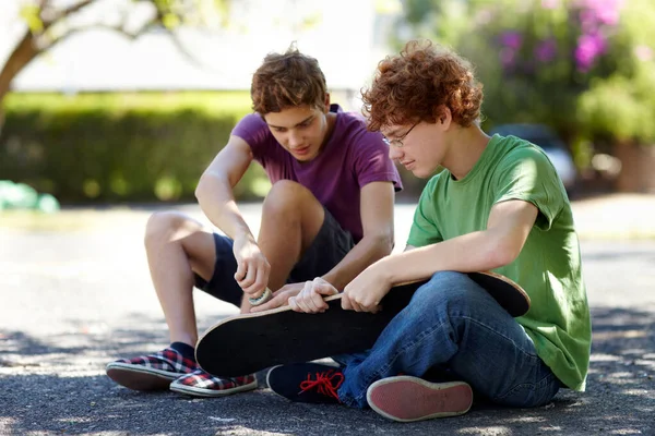 Sa come riparare il tabellone. Girato di due ragazzi adolescenti che lavorano sui loro skateboard fuori. — Foto Stock