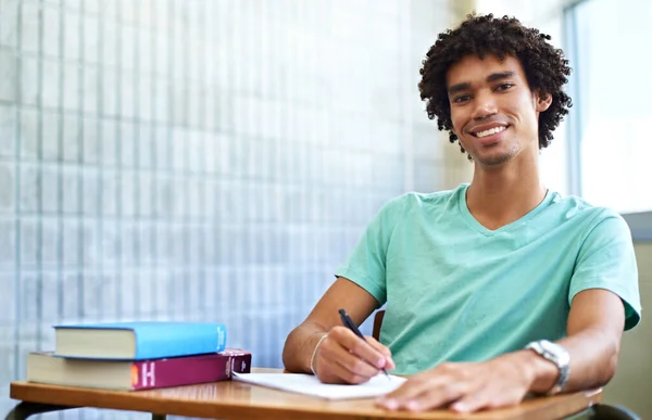 Sınavlar dert değil. Sınıfta oturan genç bir erkek öğrenci kameraya gülümsüyor.. — Stok fotoğraf