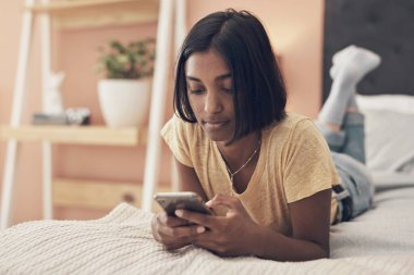 Sosyal bağlantın olmasaydı karantina ne olurdu? Evde yatağında dinlenirken akıllı telefon kullanan genç bir kadının fotoğrafı..