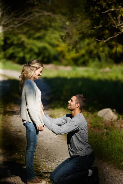 We gaan ouders worden. Schot van een man die knielt en zijn vrouw aanraakt terwijl hij geniet van een dag in het park. — Stockfoto