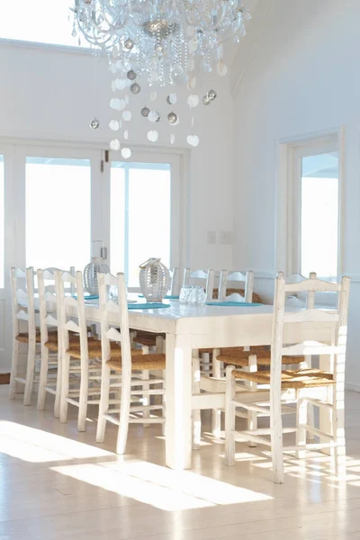 Interior blanco con mesa de comedor y sillas y lámpara de araña. Interior blanco contemporáneo con mesa de comedor y sillas y lámpara de araña. —  Fotos de Stock