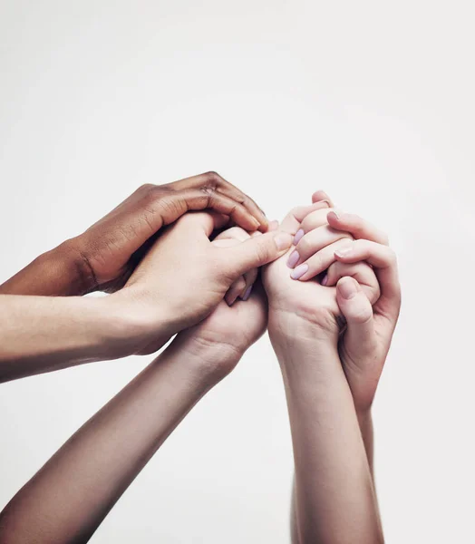 Att gå samman genom mångfald. Skjuten av en grupp händer som håller i varandra mot en vit bakgrund. — Stockfoto