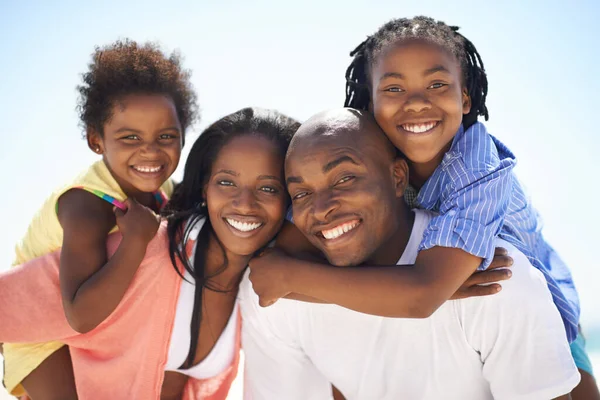 In deze tijden waardeer je familie. Twee ouders die hun kinderen een meeneem geven op het strand. — Stockfoto