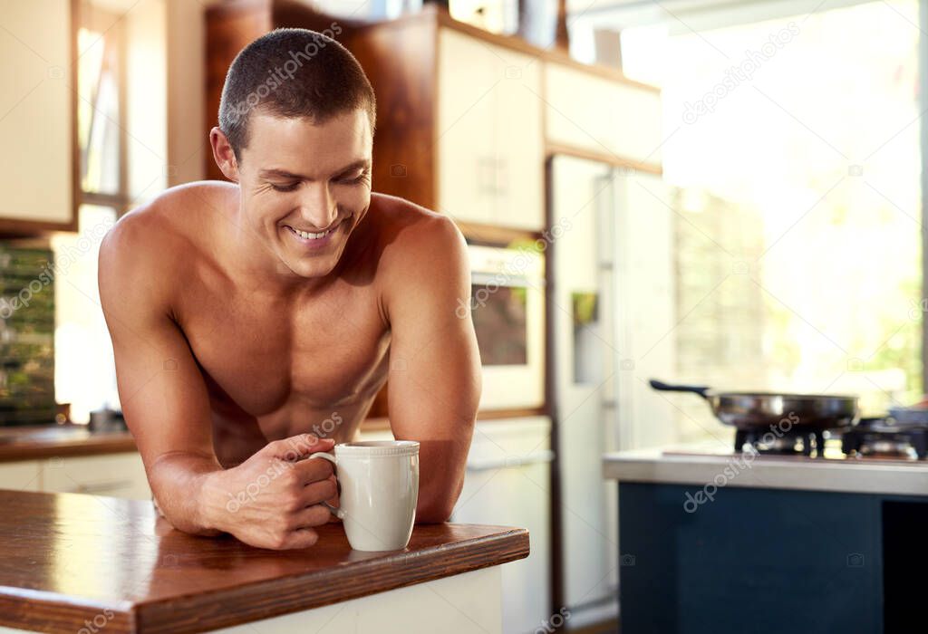 Nothing makes him happy much like coffee does. Cropped shot of handsome young shirtless man drinking a cup of coffee in the kitchen at home.