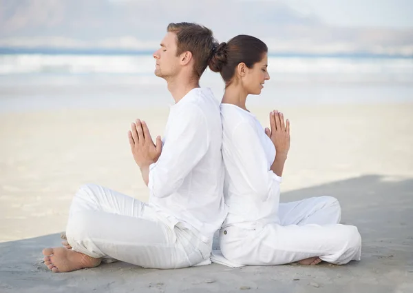 Yoga en bord de mer. Un jeune couple pratiquant le yoga sur la plage. — Photo