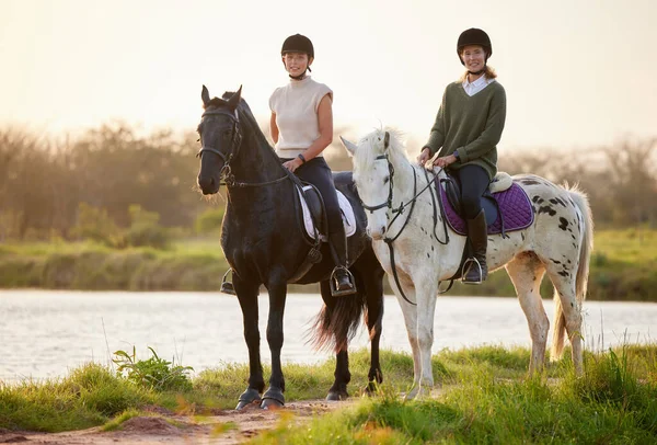 馬は強力だが雄大です。フィールドの外に自分の馬に乗って2人の若い女性のショット. — ストック写真