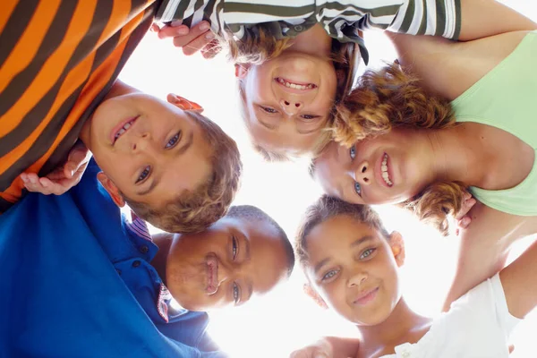 The future belongs to them. Mixed race group of children standing in a circle looking down at the camera. — Stock Photo, Image