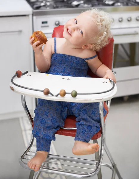 Muffin liefde. Een lieve kleine baby die een muffin eet terwijl ze in haar hoge stoel zit. — Stockfoto