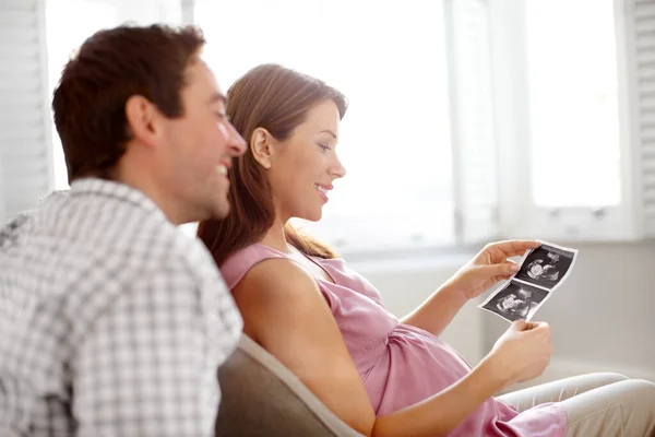 Pertama kita melihat bayi kita. Pasangan muda yang bahagia melihat gambar bayi mereka sonogram. — Stok Foto