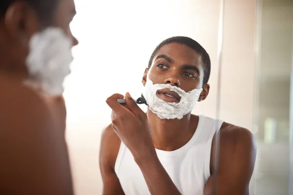 Getting rid of stubborn stubble. A young man shaving in the mirror. — Stock Photo, Image