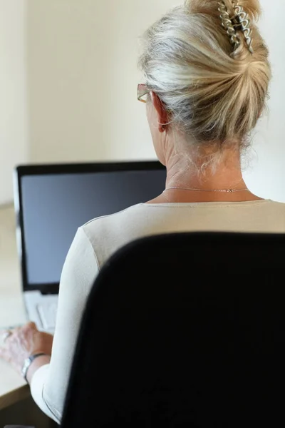 Conectada al mundo desde la comodidad de su hogar. Vista trasera de una mujer que trabaja en su portátil. —  Fotos de Stock