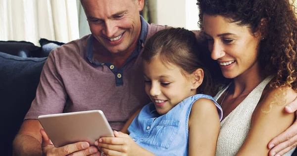 Η σύγχρονη οικογένεια είναι πιο συνδεδεμένη από ποτέ. Πυροβόλησε ένα χαριτωμένο κοριτσάκι χρησιμοποιώντας ένα ψηφιακό tablet με τη μητέρα και τον πατέρα της στον καναπέ στο σπίτι. — Φωτογραφία Αρχείου