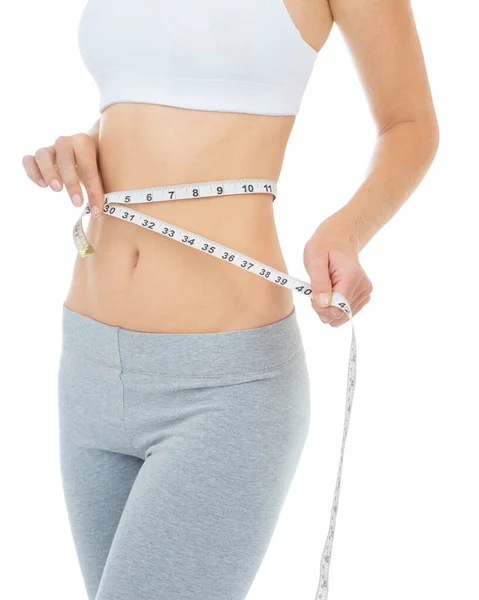 Taking off inches and feeling trim. Cropped studio shot of a woman measuring her waist with a measuring tape -Isolated image. — Stock Photo, Image