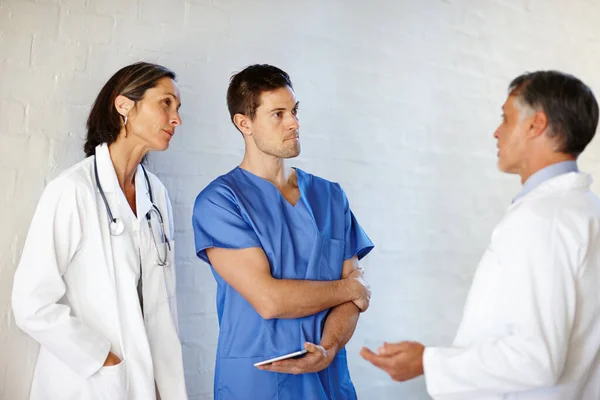 Si occupano di salvare vite umane. Una foto ritagliata di tre medici in piedi e con una conversazione seria. — Foto Stock
