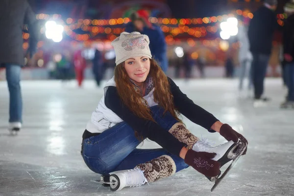 Não tenho certeza de como esticar em patins..... Retrato de uma jovem atraente sentada em uma pista de gelo esticando os braços. — Fotografia de Stock