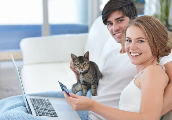 Qué familia tan feliz. Shot de una joven pareja con un gatito de compras en línea. — Foto de Stock