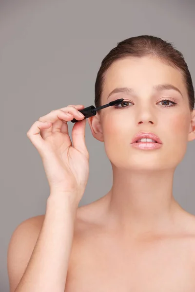 Lovely lashes. Studio portrait of a beautiful woman applying mascara. — Stock Photo, Image