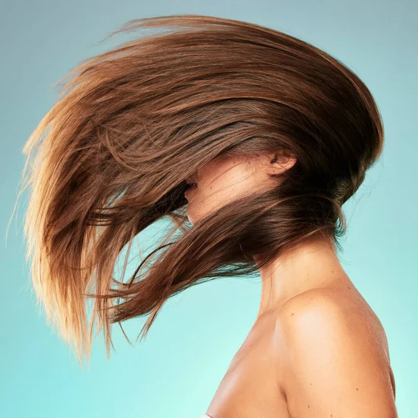Vilken fantastisk hårflipp. Studio skott av en oigenkännlig ung kvinna poserar mot en blå bakgrund. — Stockfoto