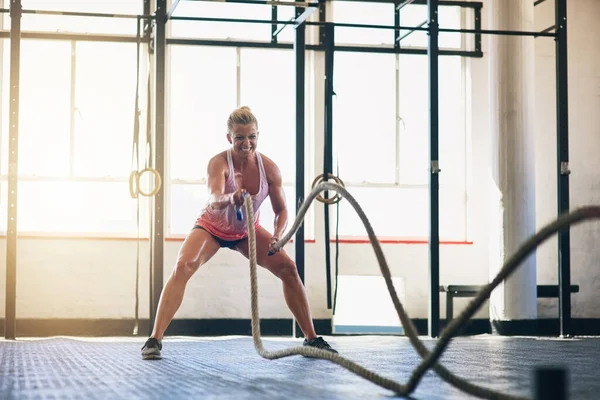 Ти стаєш сильнішою. Постріл спортивної молодої жінки, що працює з важкими мотузками в спортзалі . — стокове фото