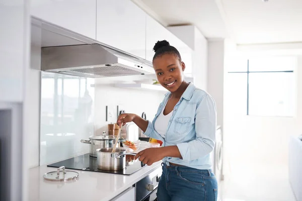 Eine herzhafte Mahlzeit macht ein Haus zu einem Zuhause. Aufnahme einer schönen jungen Frau, die zu Hause in ihrer Küche kocht. — Stockfoto