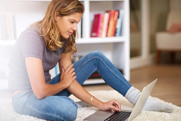Browsing her favorite websites. Shot of a young woman using her laptop at home. — Stock Photo, Image