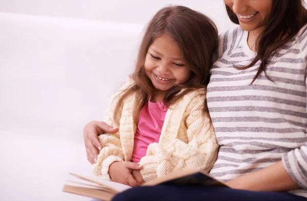彼女はおとぎ話が好きだ。家で娘に読んでいる若い母親の作物のショット. — ストック写真