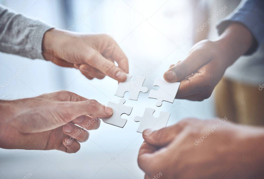 We can solve anything as a team. Closeup shot of a group of unrecognisable businesspeople holding puzzle pieces together.