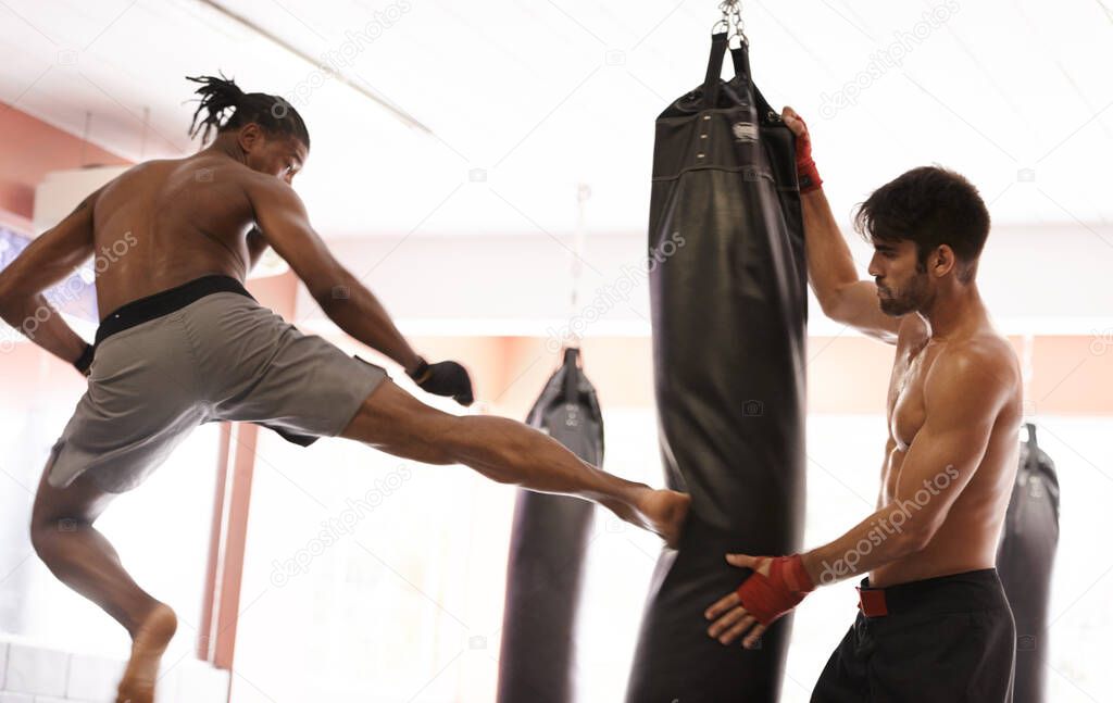 Flying knockout. Shot of a young kick boxer practicing his kicks with a partner.