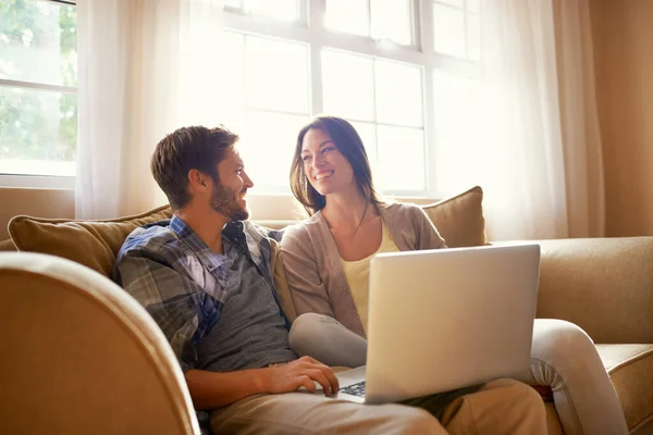 Gemeinsam lächeln über die sozialen Medien. Aufnahme eines glücklichen jungen Paares mit einem Laptop, während es auf dem Sofa sitzt. — Stockfoto