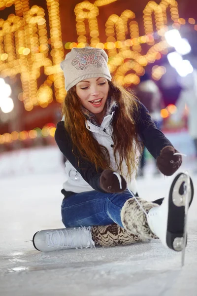 Está quase. Tiro de uma jovem mulher sentada no gelo de uma pista de patinação amarrando os atacadores de seus patins de gelo. — Fotografia de Stock