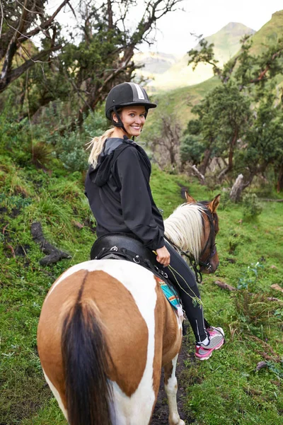 Équitation dans l'arrière-pays. Une jolie jeune femme chevauchant un cheval sur un sentier de montagne. — Photo